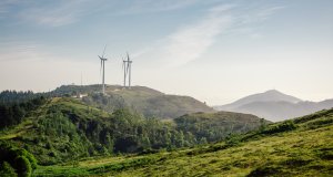 Mountain landscape on a sunny day with wind turbines generating electricity in the background.